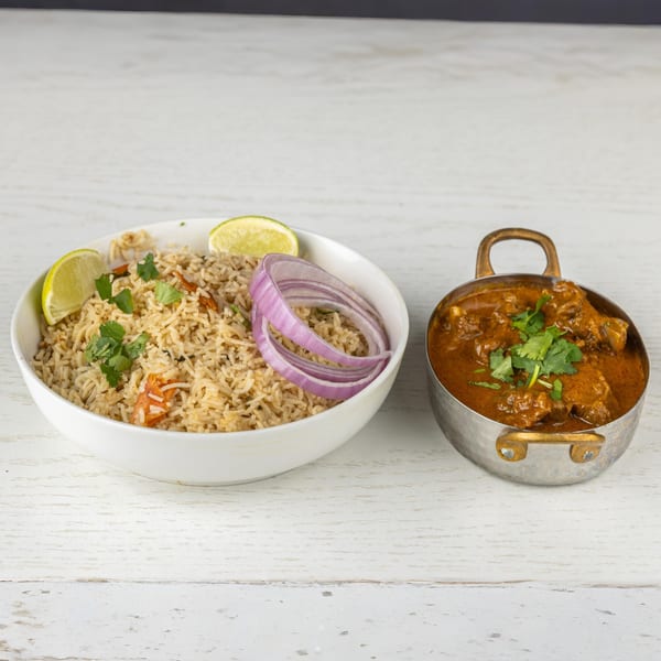 Spice Mantra's Indian biryani rice with lime and red onion, alongside a bowl of rich curry.